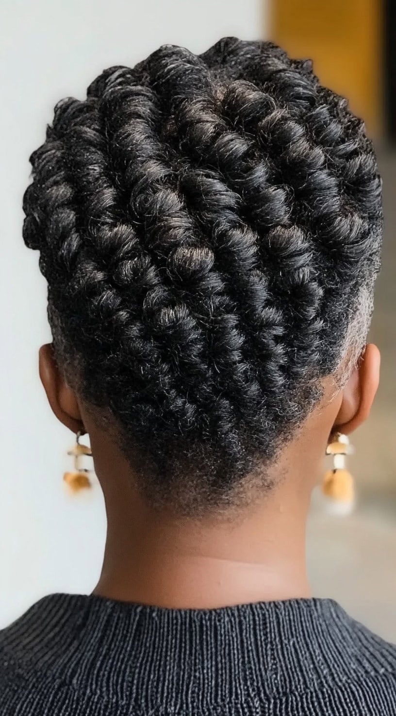 A back view of a Black woman with neatly defined flat twists arranged in a symmetrical pattern, leading into a tapered fade at the nape.