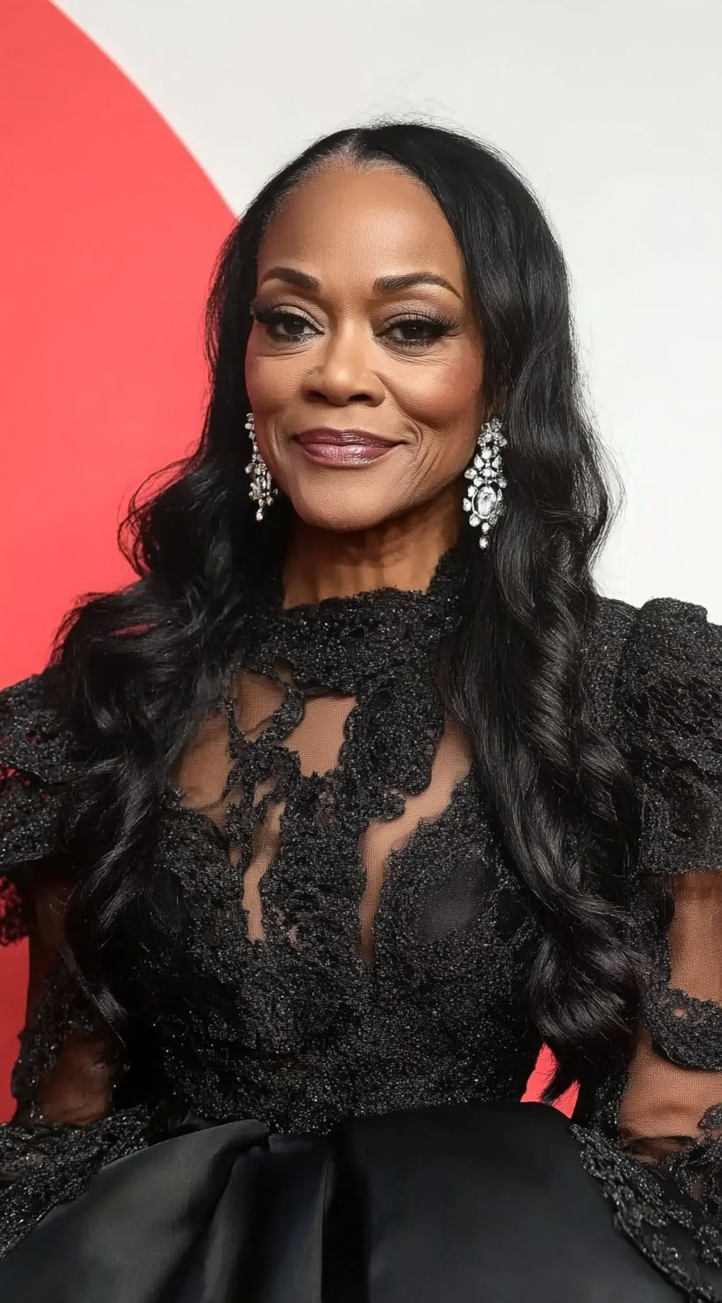 A mid-length portrait of an older Black woman with long, flowing waves parted in the middle, styled for an elegant evening look.